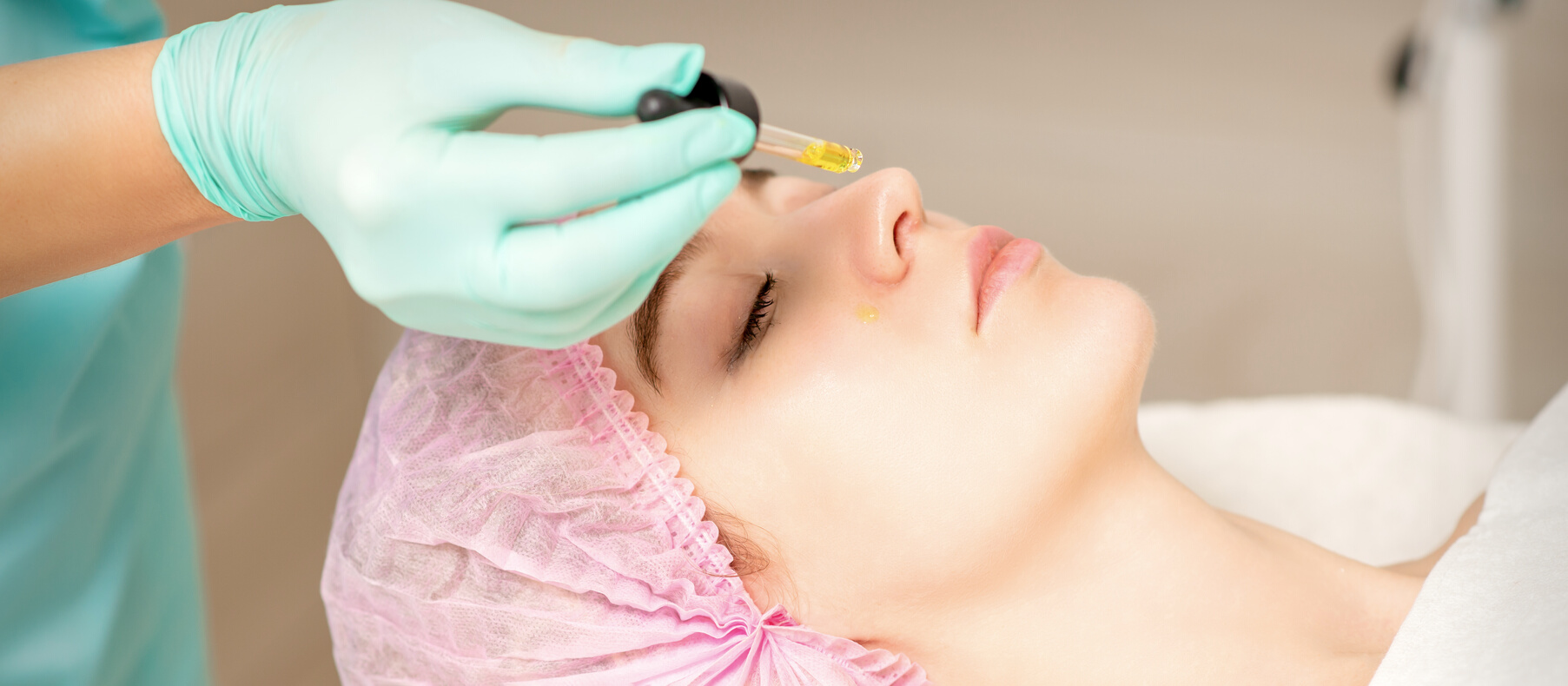 Young White Woman Getting Acid Organic Retinol Peel Face Skin with the Pipette in a Beauty Clinic.
